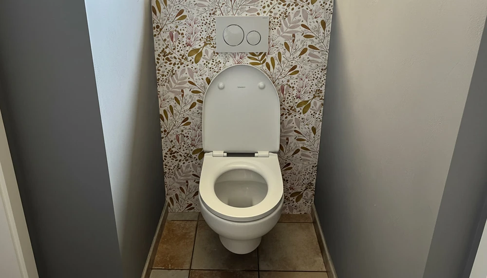 Toilettes murales modernes dans petit espace clos, murs gris et papier peint floral beige-marron