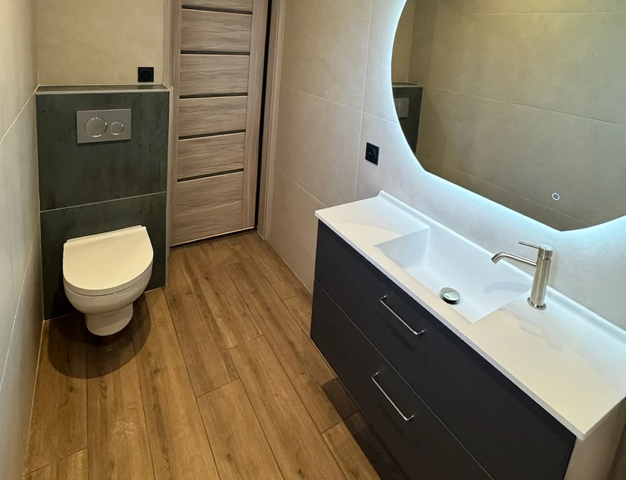 Salle de bain moderne avec toilettes suspendues murales, meuble vasque noir laqué avec plan blanc, robinetterie chromée contemporaine